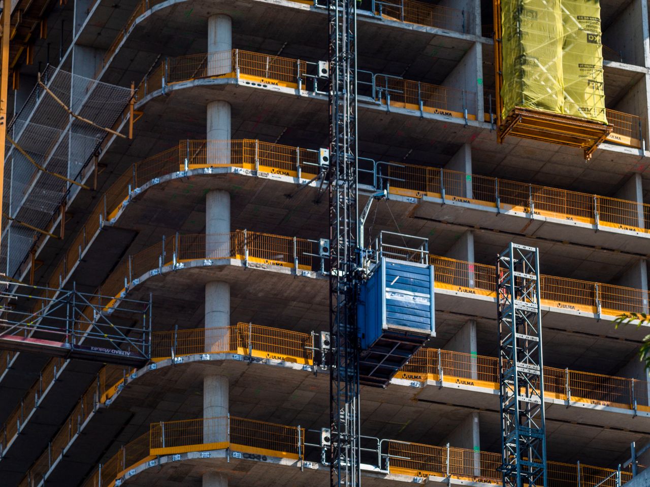 services-04 Detailed view of a high-rise building construction featuring a crane and multi-level scaffolding.