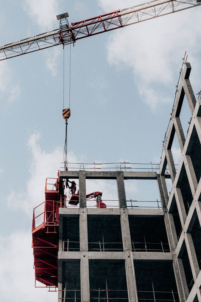 about-us From below of unrecognizable male foremen standing on half built building during work at construction site against cloudy blue sky